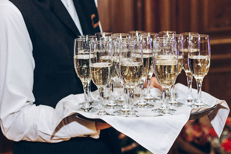 服务员在托盘上的眼镜中提供时尚的香槟优雅的酒杯在豪华婚宴上供应庆祝活动宴会背景图片