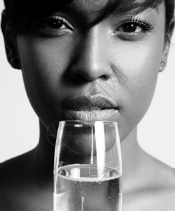 用香槟酒杯喝酒的女人的黑白特写肖像图片