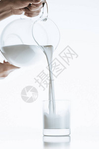将牛奶从牛奶罐倒入玻璃用白色图片