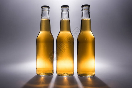 三瓶玻璃瓶啤酒在灰色背景图片