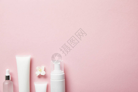 粉红色上的空化妆品玻璃瓶奶油管化妆撒图片