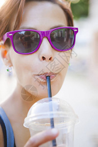 一个女人在街上解渴一个女孩在城市街道上喝鸡尾酒咖啡走黑发女郎通过管背景图片
