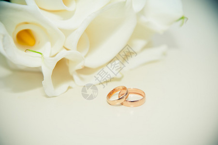 餐桌上的结婚戒指在新娘的白百合花图片