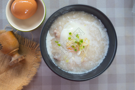 大米粥或煮猪蛋的粥切姜和蔬菜背景图片