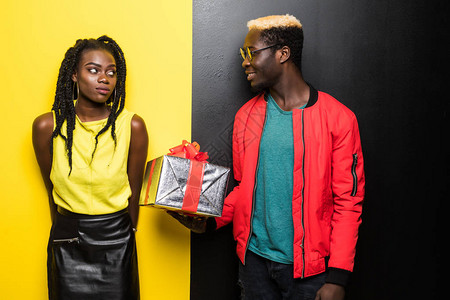 美丽的美国黑人女孩和帅哥拿着礼物看着背景图片