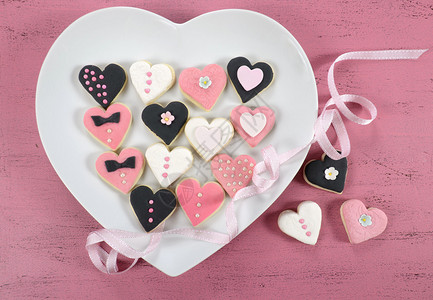 粉红色黑色和白色自制心形饼干放在白色心板上背景图片