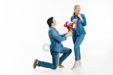 男人单膝站立给幸福的女人一束花朵将白图片