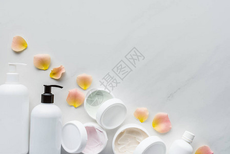 白色桌面上奶油和玫瑰花瓣的瓶子顶部视图片