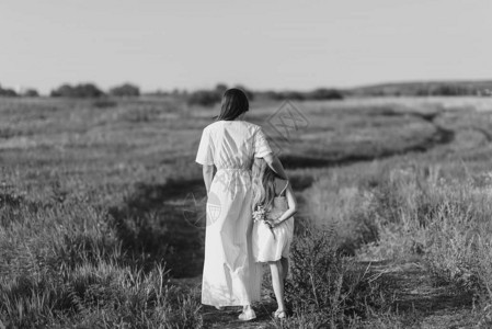 母亲和女儿在绿草原上走在农村道路图片