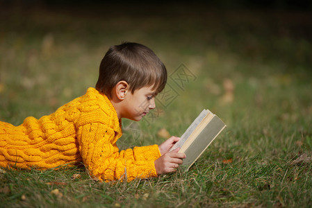 躺在草地上看书的小男孩图片