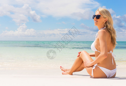 穿着白色比基尼的美女在在沙滩享受日光浴图片