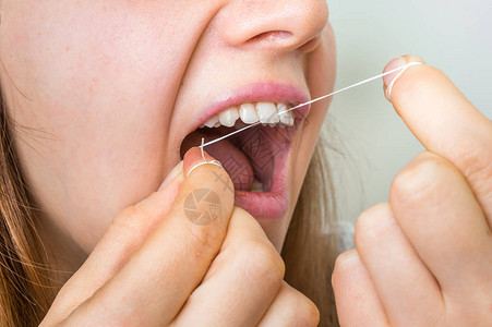 用牙线清洁牙齿的妇女口图片