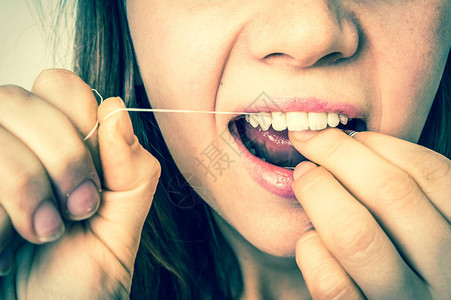 妇女用牙线打扫牙齿卫生和健康牙齿图片