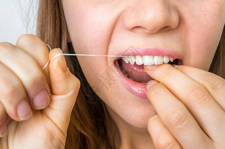 用牙线清洁牙齿的妇女卫生图片
