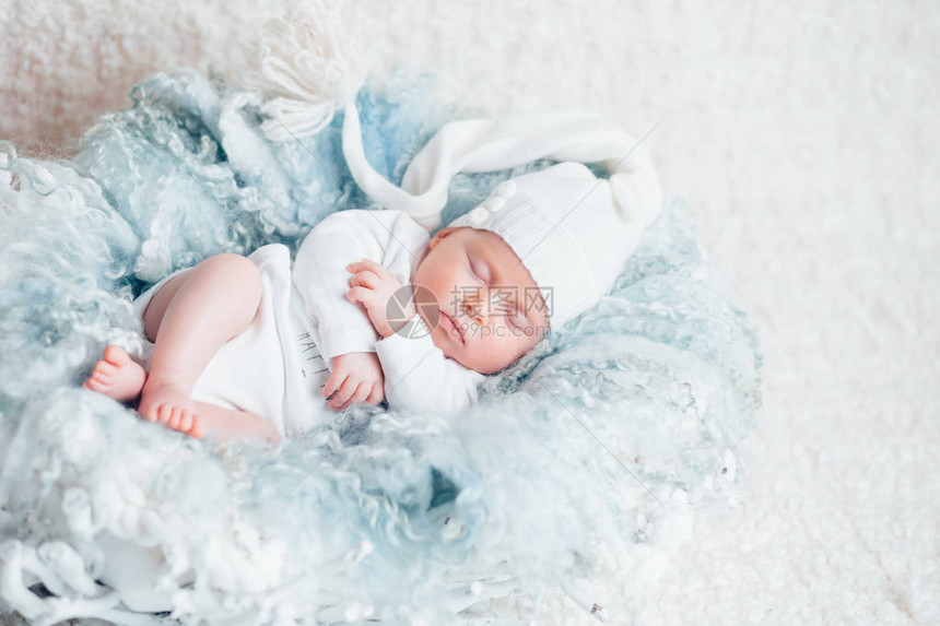 甜蜜的梦中的甜蜜宝贝新生儿两周穿着白色衣服睡在浅蓝色图片