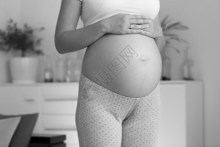 孕妇手放在大肚皮上的黑白特写照片图片