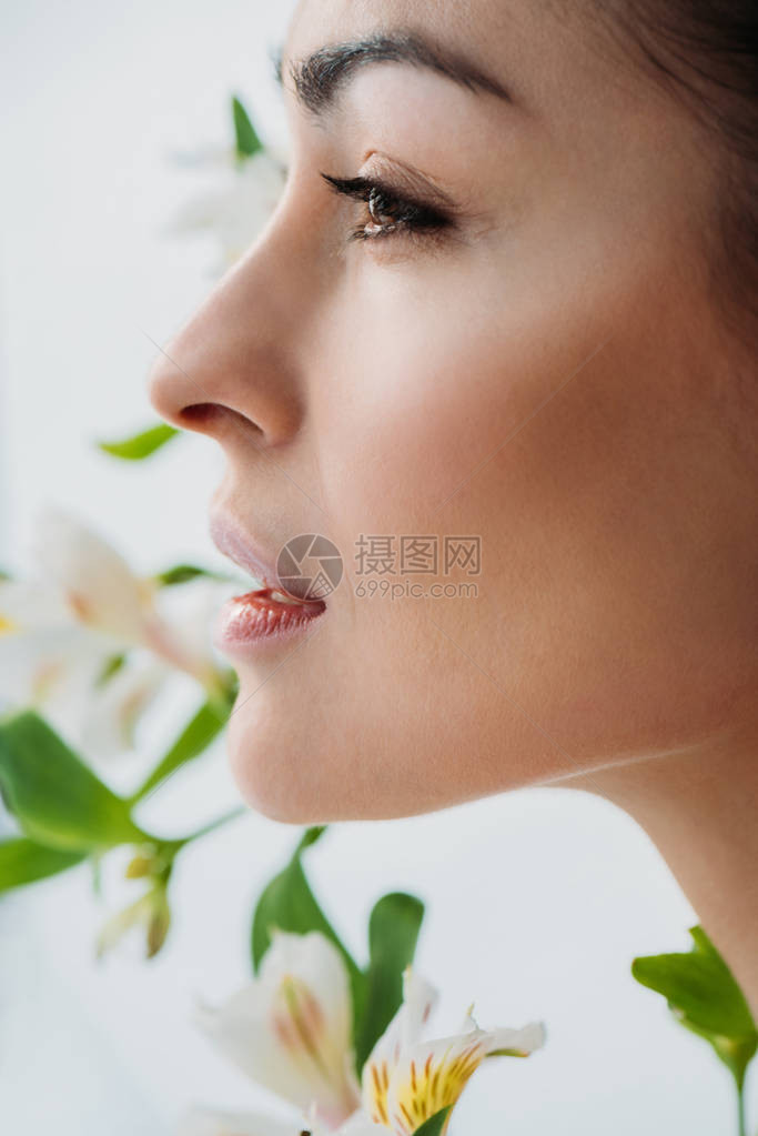 长着白色百合花在背景中装扮的年轻美皮肤女青图片