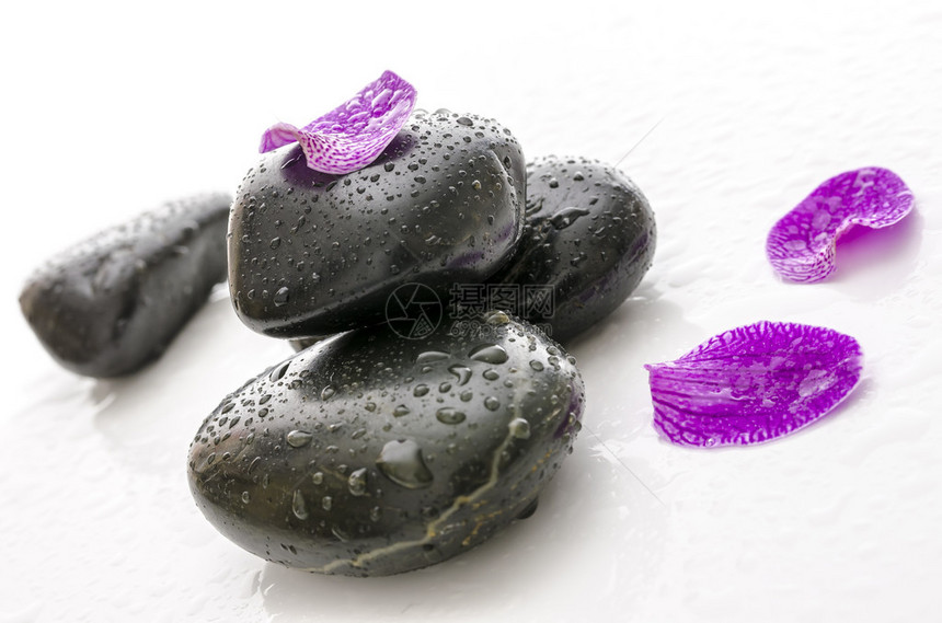 黑色spa石头上的紫色花瓣与水滴图片