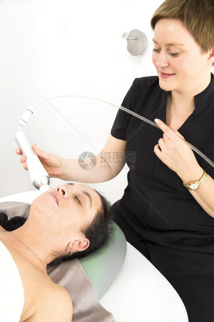 在美容和水疗沙龙对一位闭眼的顾客进行钻石磨削剥皮肤提升图片