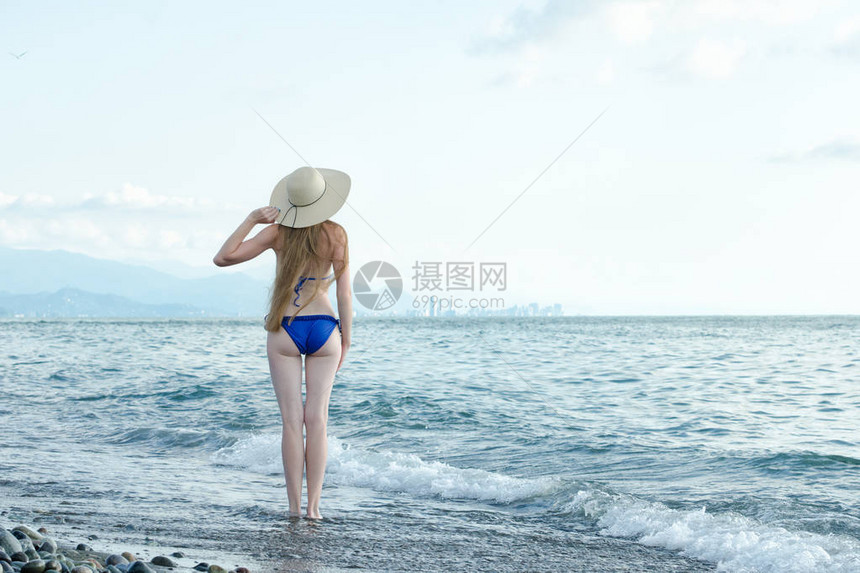 穿着泳衣和帽子的女孩站在海图片