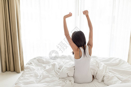 早上醒来后躺在床上伸展的女人图片