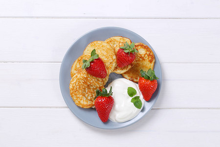一盘美国煎饼配白酸奶和新鲜草莓在白色木质背景上图片