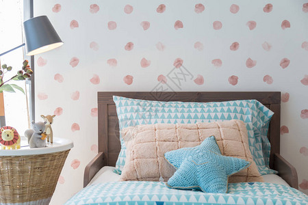 木床上的星形枕头和方形枕头配有动物娃和卧室孩子的床头灯图片