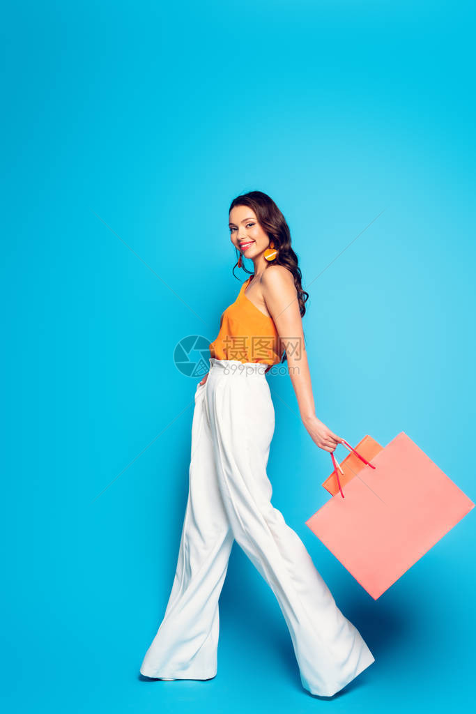 满的景象是喜悦的时髦妇女带着粉红购物袋行走图片