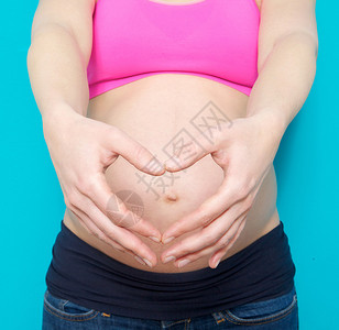 怀孕的年轻孕妇在肚子前露出心脏标图片