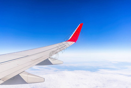 从云上方蓝天的飞机右翼窗口中图片