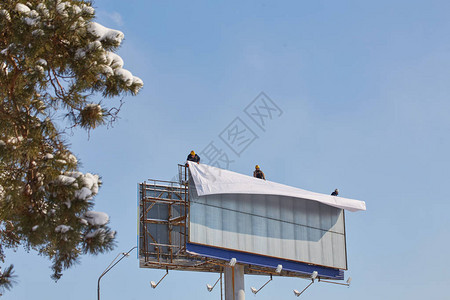工人准备广告牌以安装新广告在梯子上工作的工业登山者图片