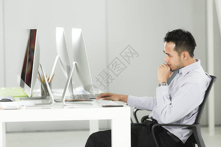 亚洲年轻商人坐在办公桌前的电脑屏幕前图片