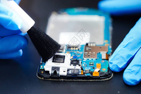 亚洲技术员用刷子修理和清洁智能手机电子技术的脏微电路主板图片