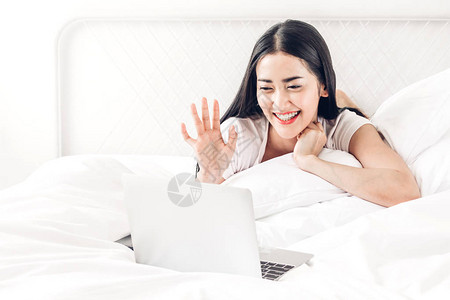 快乐的女人在家的床上放松和使用数字笔记本电脑女人检查社交应用程序并图片