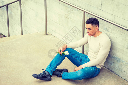 年轻的美国男子穿着浅灰色针织毛衣蓝色牛仔裤黑色运动鞋图片