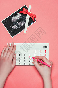 女在日历超声波扫描和以粉红色隔离丝带进行怀孕测试时做笔图片