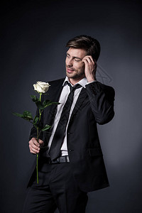 身穿西装的年轻男子拿着白玫瑰望图片