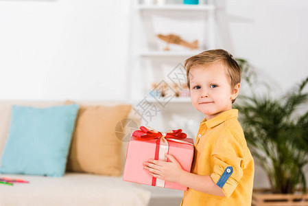 小男孩手里拿着包裹好的礼物的侧视图图片
