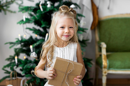 有圣诞节礼物盒的愉快的小微笑的女孩圣诞快图片
