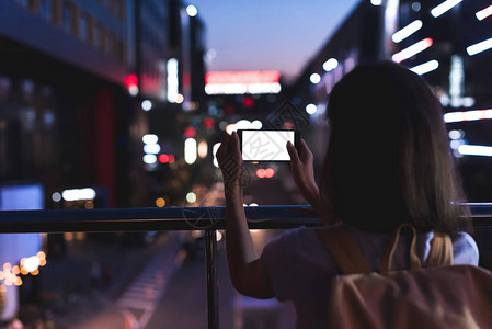 背着包和智能手机手拿着空白屏幕站在夜市街上图片