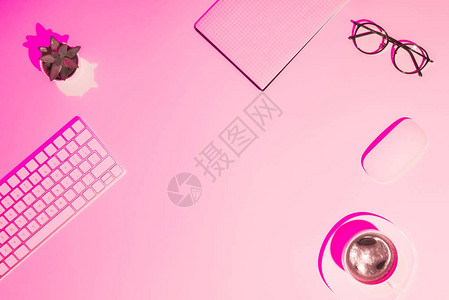 粉红色的咖啡杯植物眼镜空教科书计算机键盘和桌上鼠图片