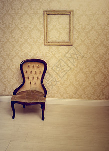 贴着墙纸的房间里的古董软垫椅子图片