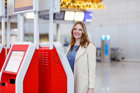 出差回家过圣诞节的年轻女子在国际机场通过电子终端办理登机手续候机楼的女乘客图片