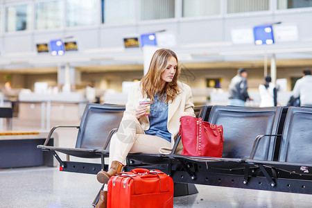 国际机场的女商人坐着喝咖啡去等待她出差的航班图片