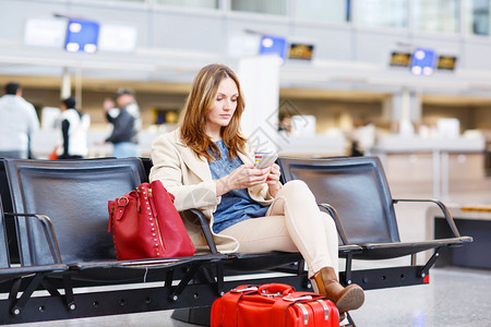 国际机场的年轻女子坐在等待取消或延误的航班图片