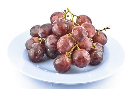 白色背景盘子上的红葡萄果实图片