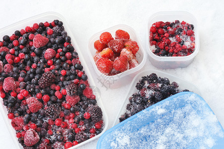 雪中冷冻混合浆果的塑料容器图片