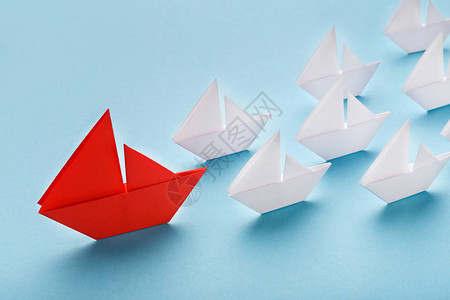 舆论领袖影响者概念一艘红船带领蓝底小白船航行蓝色背图片