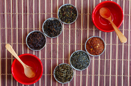 黑茶绿茶和红碗中的木勺子放在棕竹子垫上高清图片