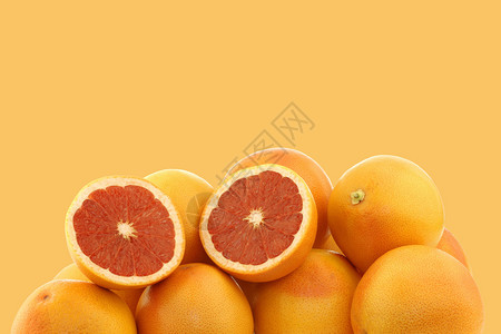 新鲜的红葡萄柚和橙色背景上的切开的葡萄柚图片